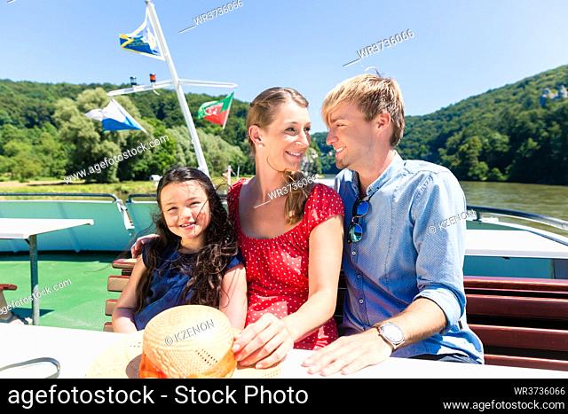 Happy family sitting on boat on river cruise in summer