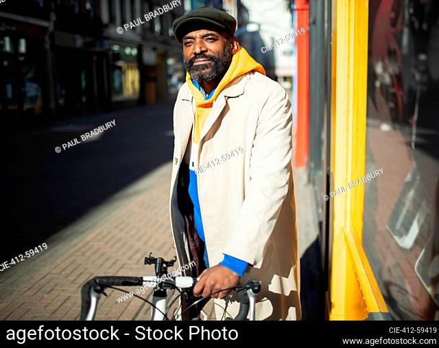 Portrait handsome man with. bicycle at sunny city storefront
