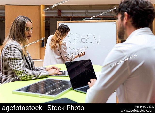 Businessman using laptop in office with solar panel on table