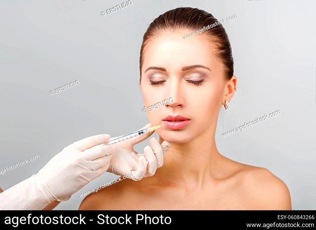 Portrait of young beautiful woman getting cosmetic lifting injection in lips. Plastic Surgery. Cosmetic Treatment