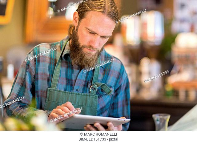 Caucasian server using digital tablet in cafe