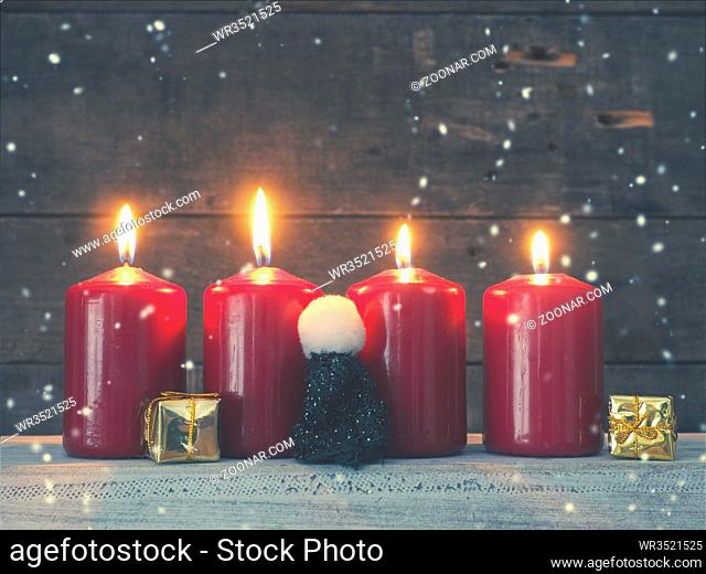 Four red Advent candles on a rustic wooden background, First candle is burning, Christmas concept background