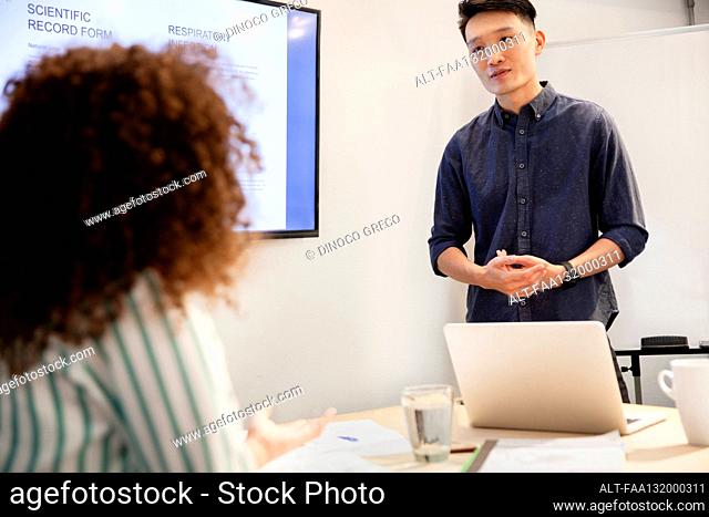 Project manager listening to female coworker during presentation