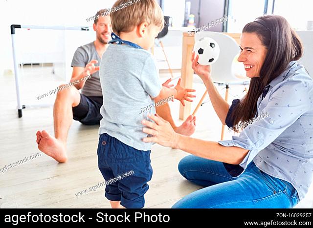 Glückliche Mutter beim Ball spielen mit ihrem Sohn und mit Vater im Hintergrund