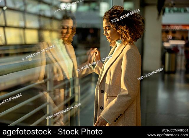 Thoughtful young woman looking through window at station