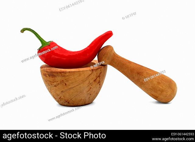 Old rustic wooden pestle and mortar alongside an fresh red chili pepper isolated on a white background