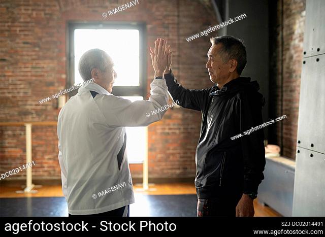 Two senior men doing hi-five