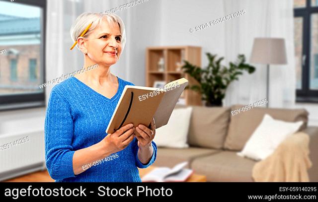 senior woman with pencil and diary or notebook
