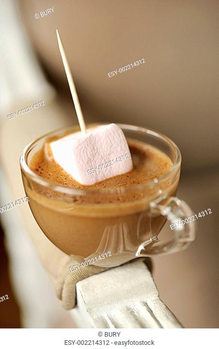Dripping a marshmallow in a cup of chocolate cream