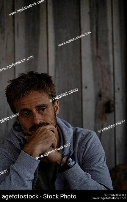 Sad man sitting in stilt hut