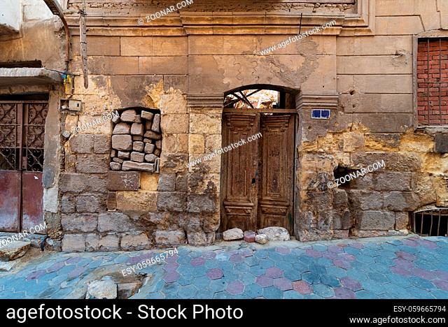 Grunge stone bricks wall with Broken wooden door and closed broken window in abandoned Darb El Labana district, Cairo, Egypt