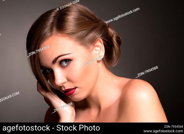 Sexy beautiful woman looking so sad isolated on dark background. Blond lady with red lips in photo studio
