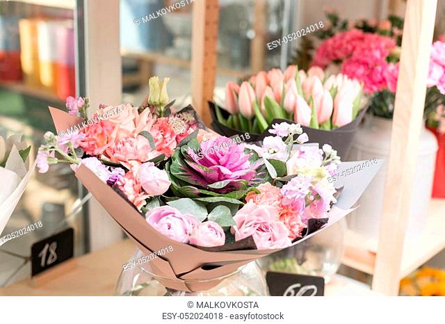 Flower shop concept. Different varieties fresh spring flowers in refrigerator for flowers. Bouquets on shelf, florist business