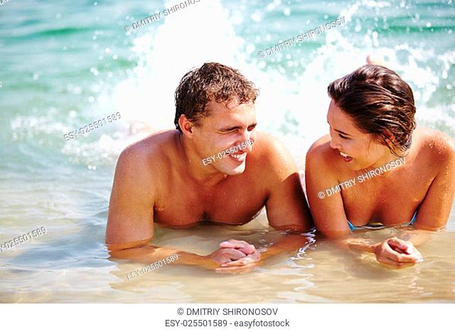 Ecstatic young couple splashing in water during vacations