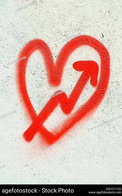 Red heart painted on white wall and cupid arrow