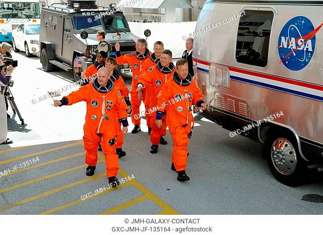 The STS-121 crewmembers, having donned their shuttle launch and entry suits, wave flags for the Fourth of July as they prepare to board the transfer van...