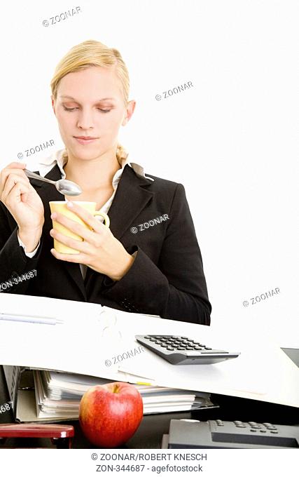 Blonde Geschäftsfrau am Schreibtisch trinkt ruhig aus einer Tasse