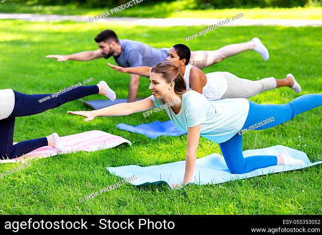 group of people doing yoga at summer park