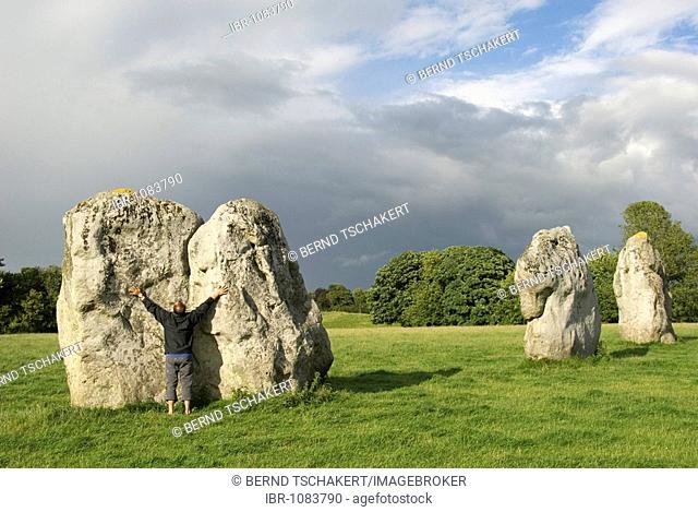 Man touching a big stone, outstretched arms, stone circle, Avebury, Wiltshire, England, Great Britain, Europe