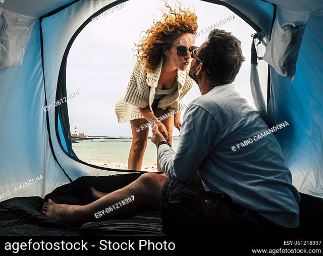 Love and kiss in free tent camping vacation for adult beautiful couple at the beach - freedom and happy lifestyle people travel and enjoy the tent camping with...