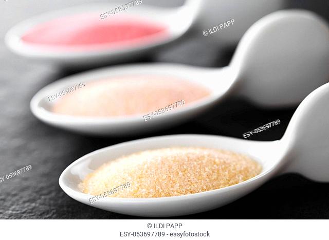 Yellow, orange and red instant jelly or jello powders on small spoons, photographed on slate (Selective Focus, Focus one third into the yellow powder)