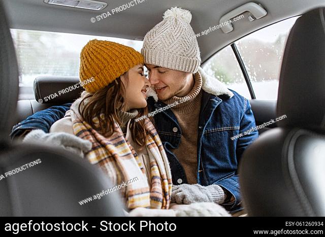happy smiling couple on car back seat in winter