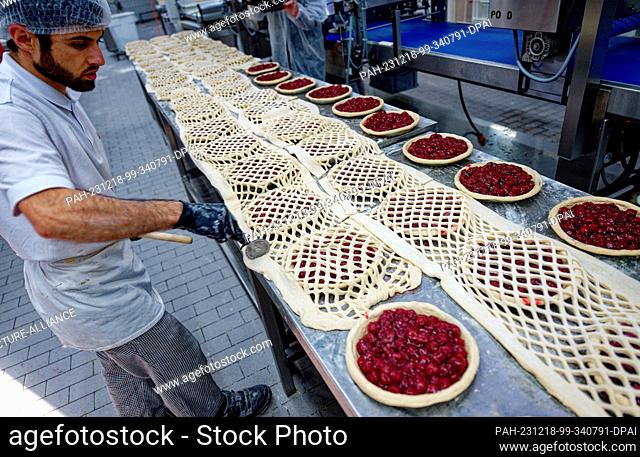 18 December 2023, North Rhine-Westphalia, Aachen: An employee works on cakes at the Nobis Printen bakery. Photo: Henning Kaiser/dpa
