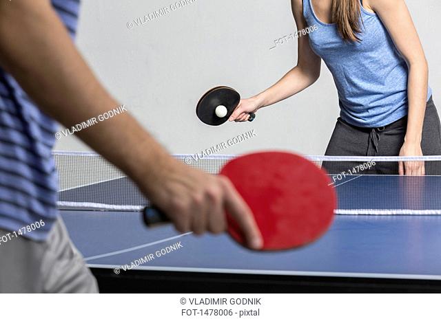 Midsection of man and woman playing table tennis