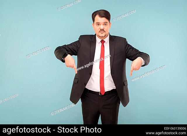 Now that you look down. indoor studio shot. isolated on light blue background. handsome businessman with black suit, red tie and mustache looking at camera