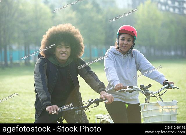 Portrait teen twins on bicycles in park