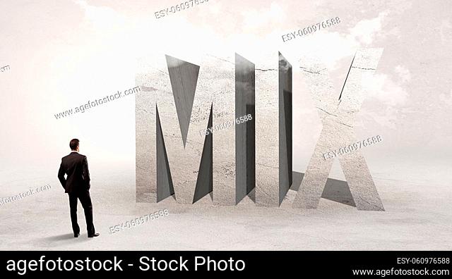 Rear view of a businessman standing in front of MIX abbreviation, attention making concept