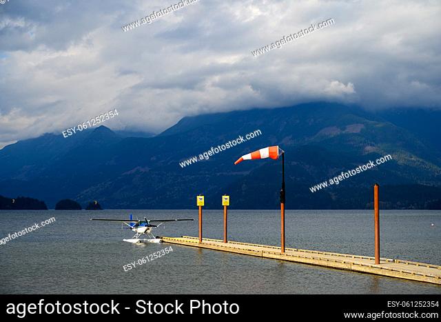 Hydroplane tied to the water aerodrome on Harrison Lake and the wind blowing into a windsock over blue and cloudy sky in Harrison Hot Springs, British Columbia