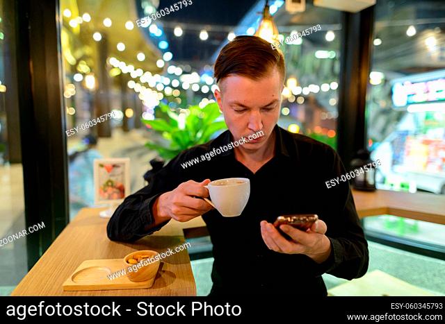 Portrait of young handsome Scandinavian businessman relaxing at the coffee shop