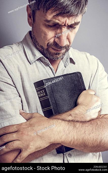 man holding a bible and praying
