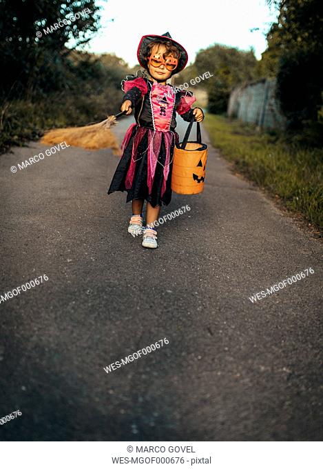 Little girl masquerade as a witch with halloween lantern and broom