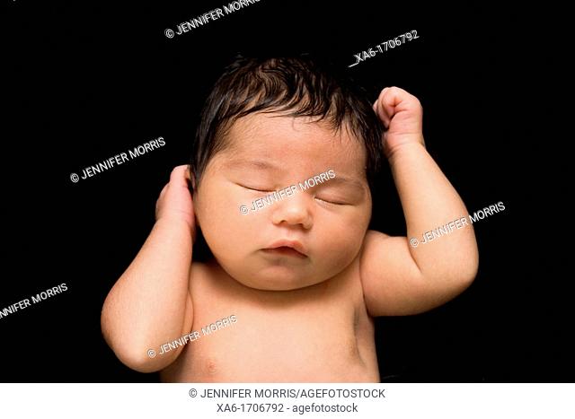 A newborn baby lies sleeping  Lots of hair  Close up