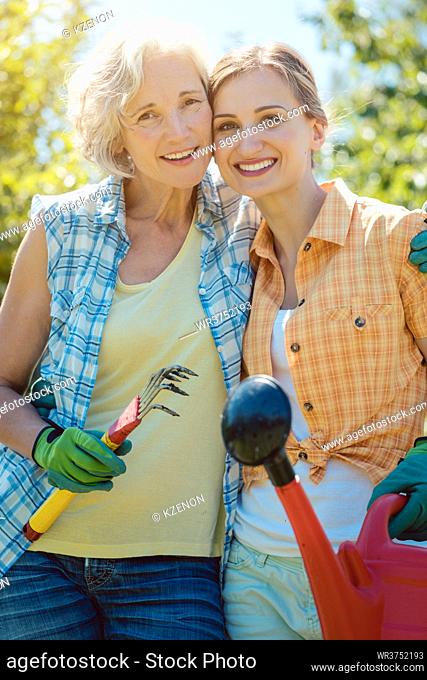 Woman gardening together in summer looking at each other
