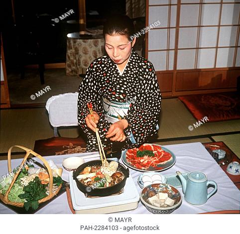 A Japanese woman in a traditional kimono preparing Shabu Shubu, a Japanese specialty consisting of thin slices of meat, tofu, eggs and fresh vegetables