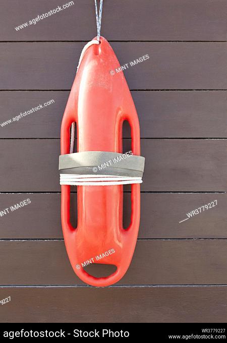 Orange lifeguard buoy, a safety float hanging on a wood wall