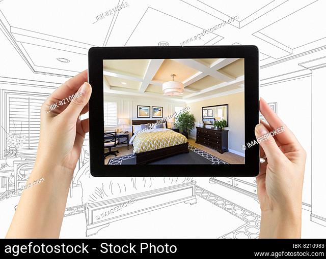 Female hands holding computer tablet with bedroom photo on screen, drawing behind