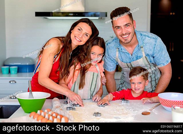 Happy caucasian family baking together, making cookies in kitchen