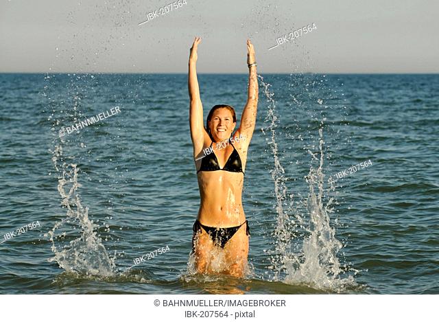 Young woman jumps in the water