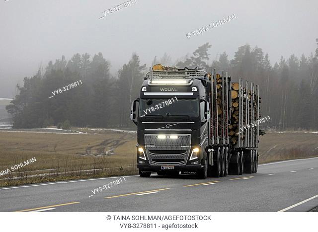Salo, Finland - March 15, 2019: Beautiful headlights and led lights of Volvo FH16 750 logging truck of Wolin Ky light up rural road on a foggy day