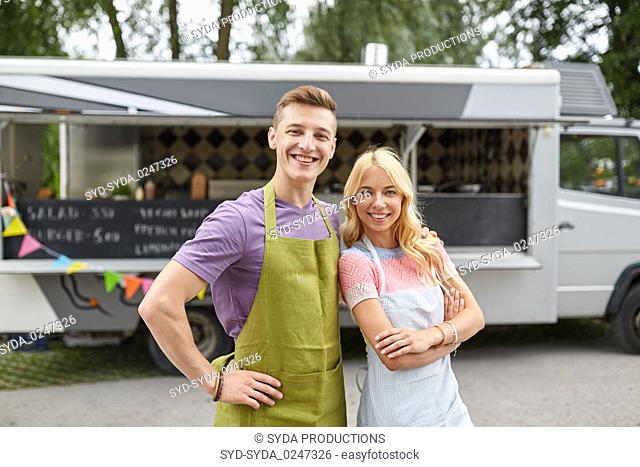 happy couple of young sellers at food truck