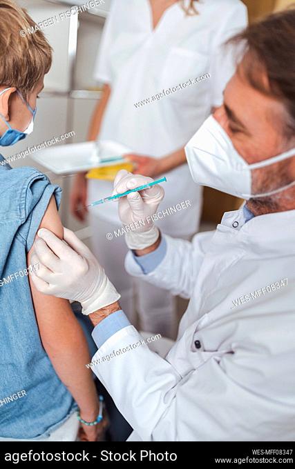 Doctor administering vaccine to boy at vaccination center