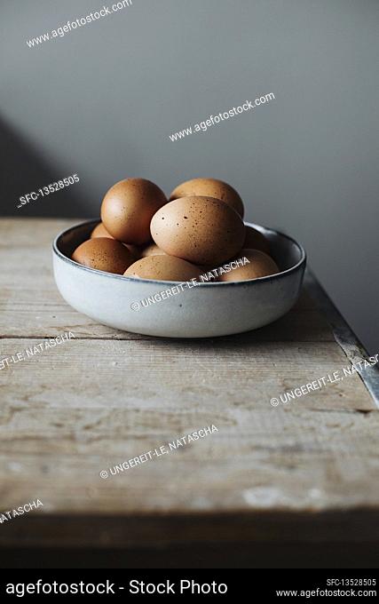 Fresh eggs in a bowl on a wooden table