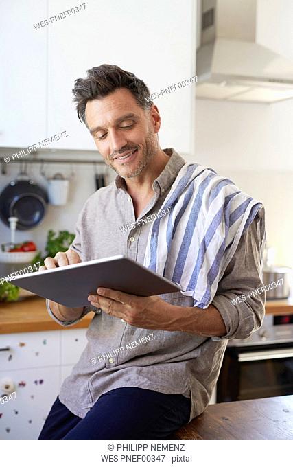Portrait of smiling man using tablet in the kitchen