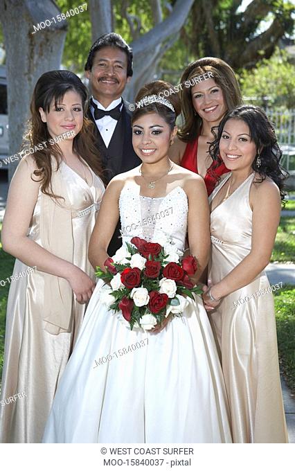 Portrait of girl 13-15 with parents and friends in garden at Quinceanera
