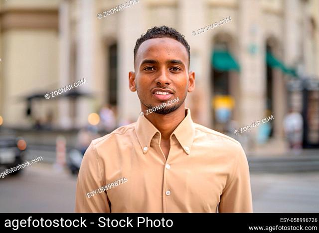 Portrait of handsome black young African businessman wearing casual clothes outdoors in city