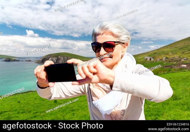 senior woman taking selfie by smartphone on beach